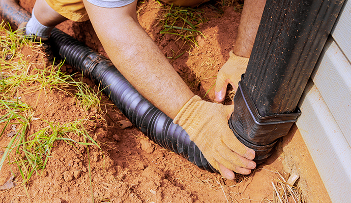 Backyard downspout installation by worker Worker installing a new downspout in a residential backyard